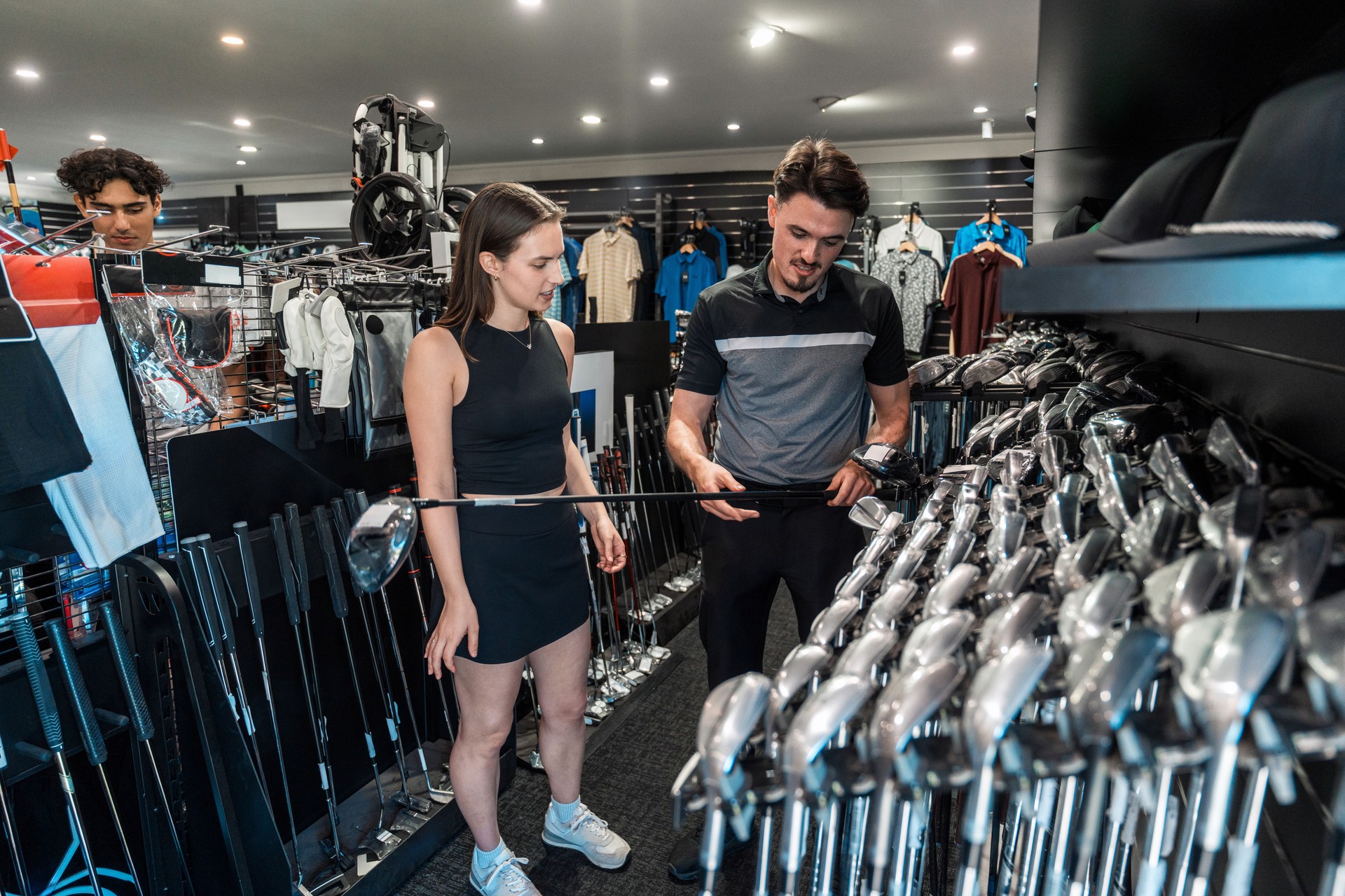 Enthusiastic Caucasian Female Selects Golf Club with Expert Guidance