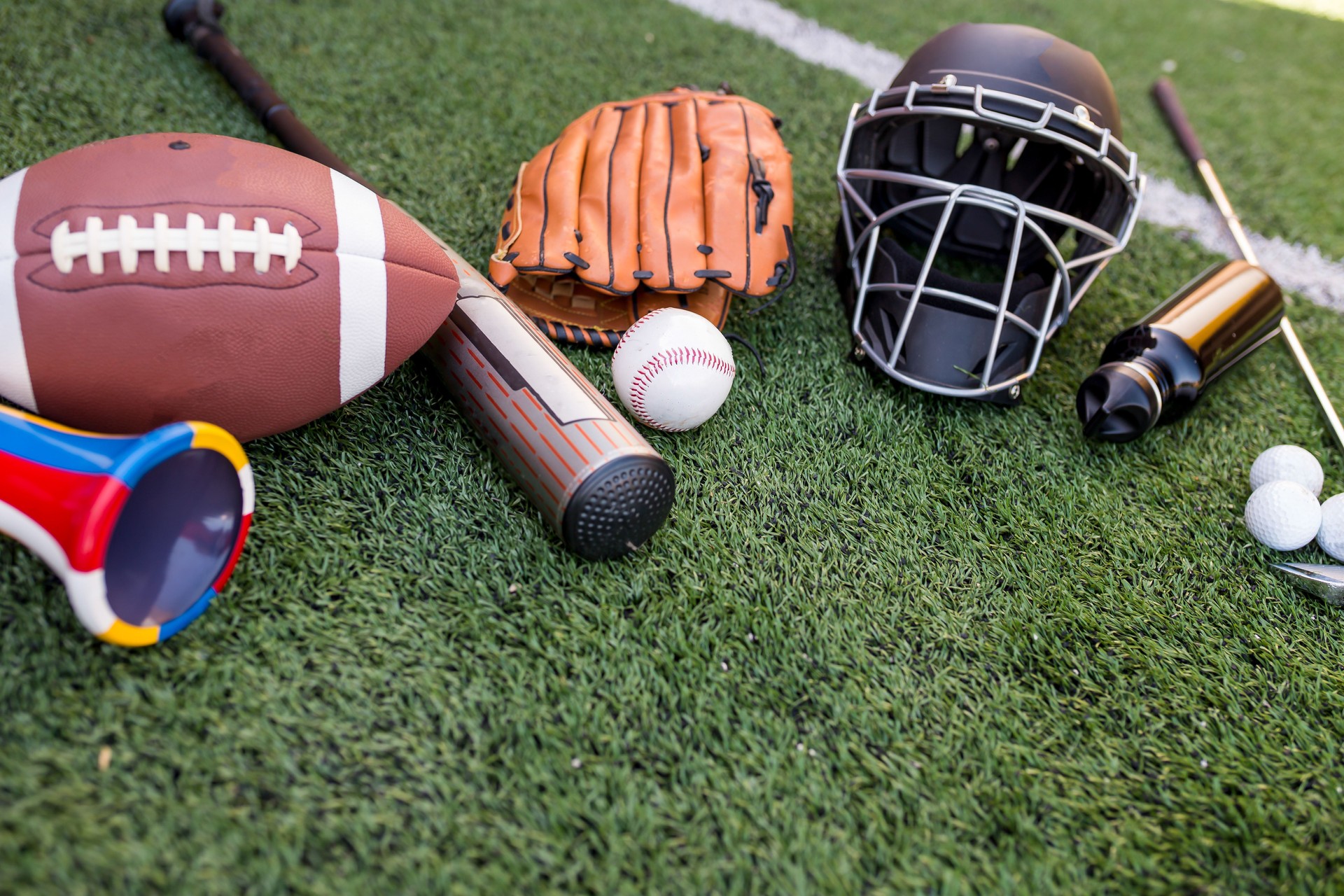 Huge collection stack of sport balls gear equipment from various sports on green grass soccer field concept
